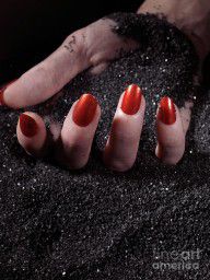 2810227_Woman_Hand_With_Red_Nails_On_Black_Sand